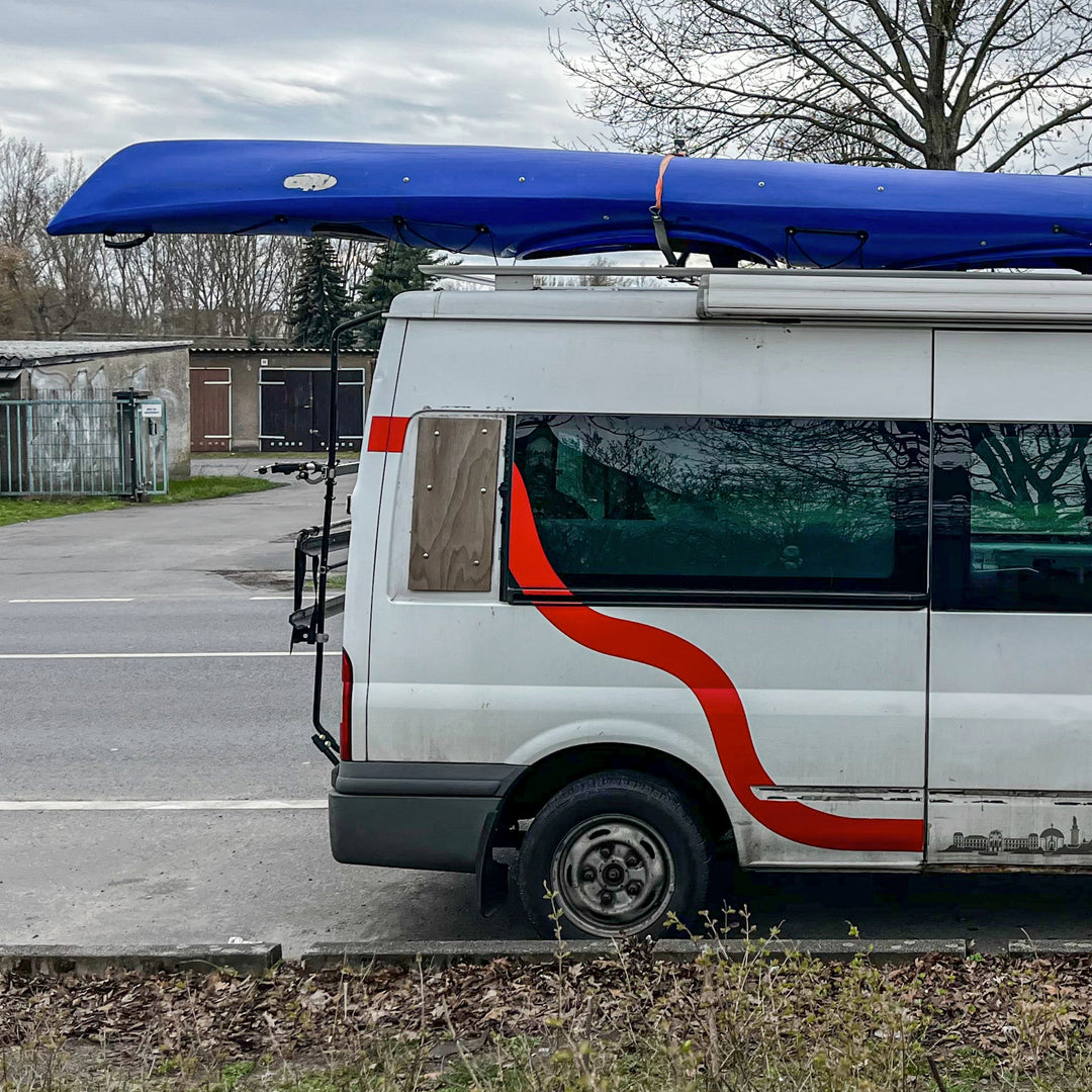Kajak wird auf einem Autodach befestigt mit Spanngurten