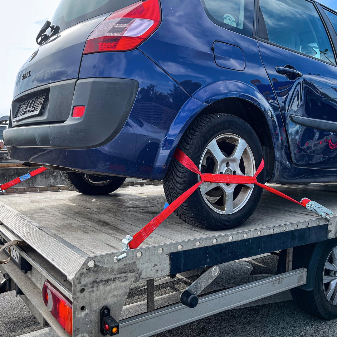 Auto wird mit Spanngurten auf einem Anhänger befestigt